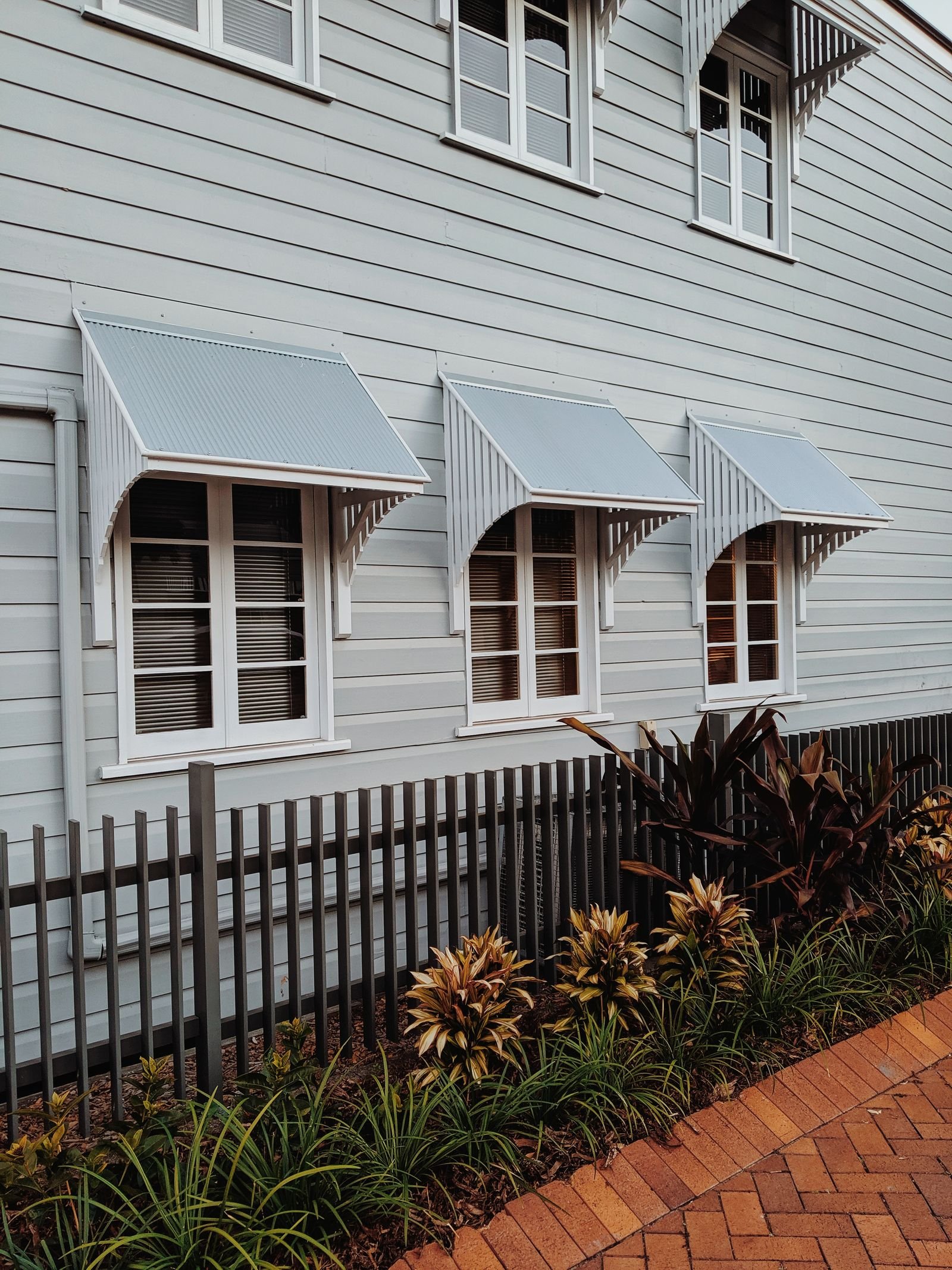 Fixed metal window awnings projecting from a weatherboard house