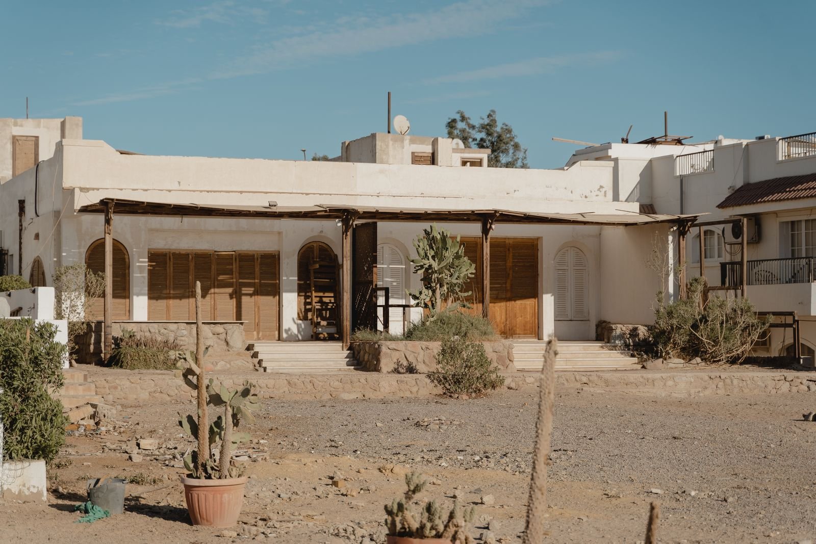 Adobe building with a deep covered porch and desert planting