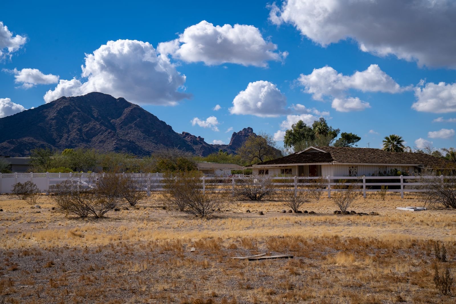 Open Arizona ranch land with a distant mountain and scattered buildings