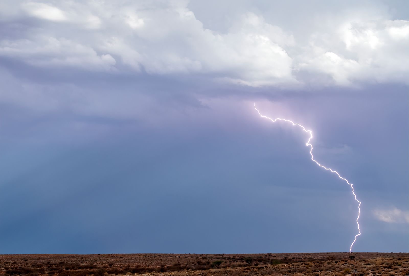 Lightning striking from a storm cloud over open desert